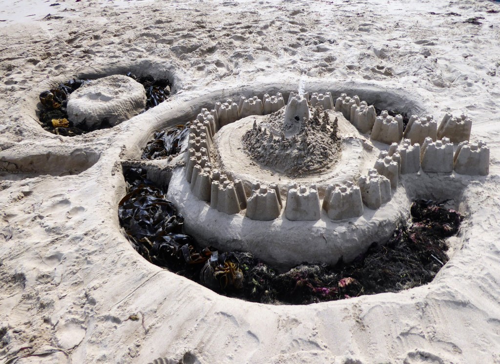 elaborate sandcastle with moat filled with seaweed